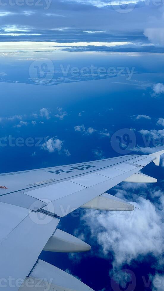 Aerial View from Airplane Wing Over Clouds and Coastline photo