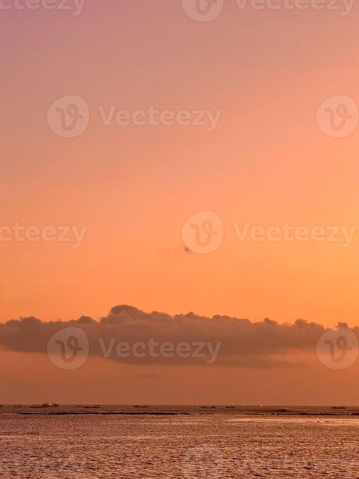 golden sunset over Kelan Beach, Bali, with calm ocean waves and a scenic breakwater. A tranquil coastal scene with warm hues serene atmosphere. photo