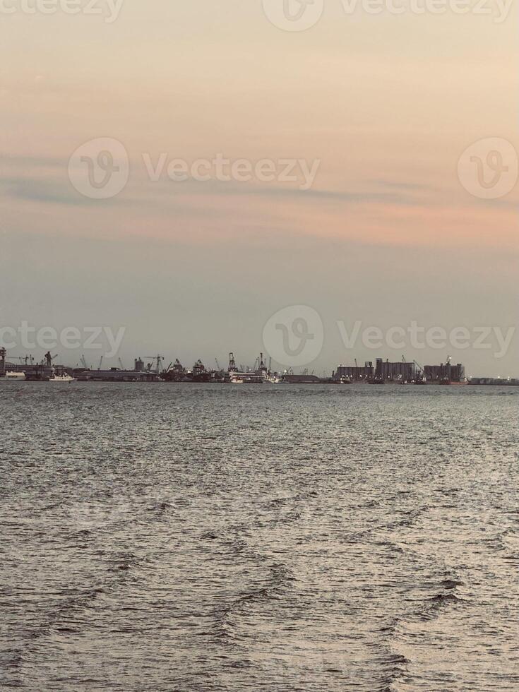 Orange Sunset Over Suramadu Bridge, View from Surabaya to Madura with Harbor and Silhouettes of Ships on the Horizon. A Scenic Twilight Over the Ocean, Dramatic Clouds, Vibrant Sky, Coastal Landscap photo
