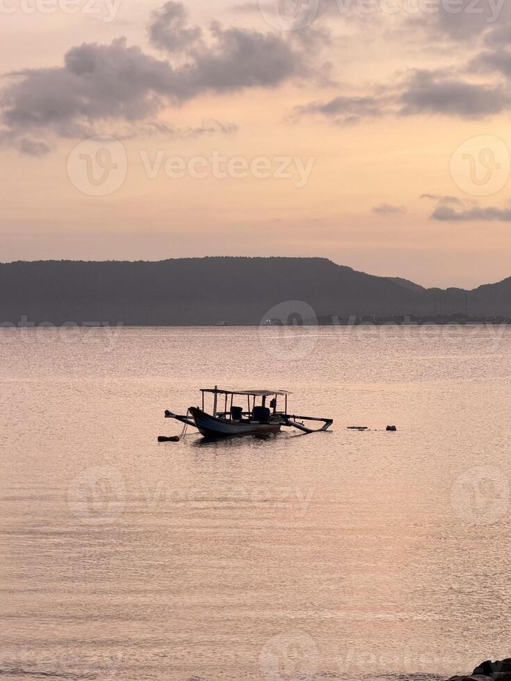 Serene Sunrise with Fishing Boat and sitant island on Calm Waters. Plengsengan Beach Banyuwangi, Bali Strait photo