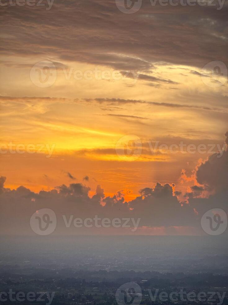 Dramatic Sunset with Fiery Clouds Over a Distant Landscape photo