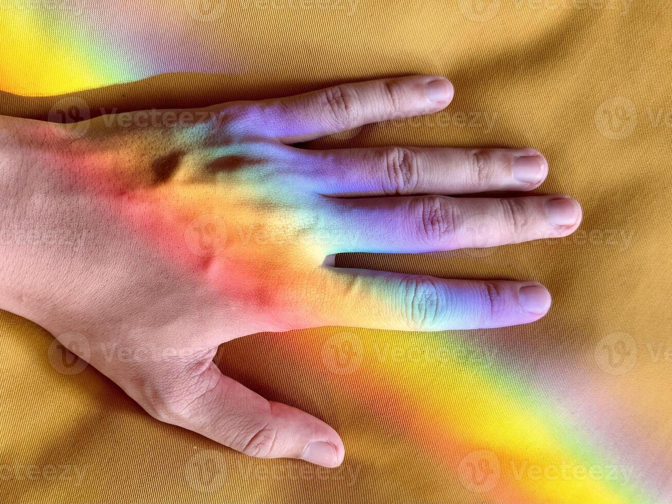 Hand with Rainbow Reflection on Yellow Fabric photo