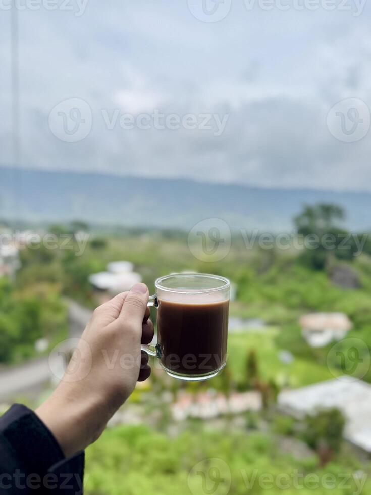 Coffee in Hand with Scenic Greenery Background photo