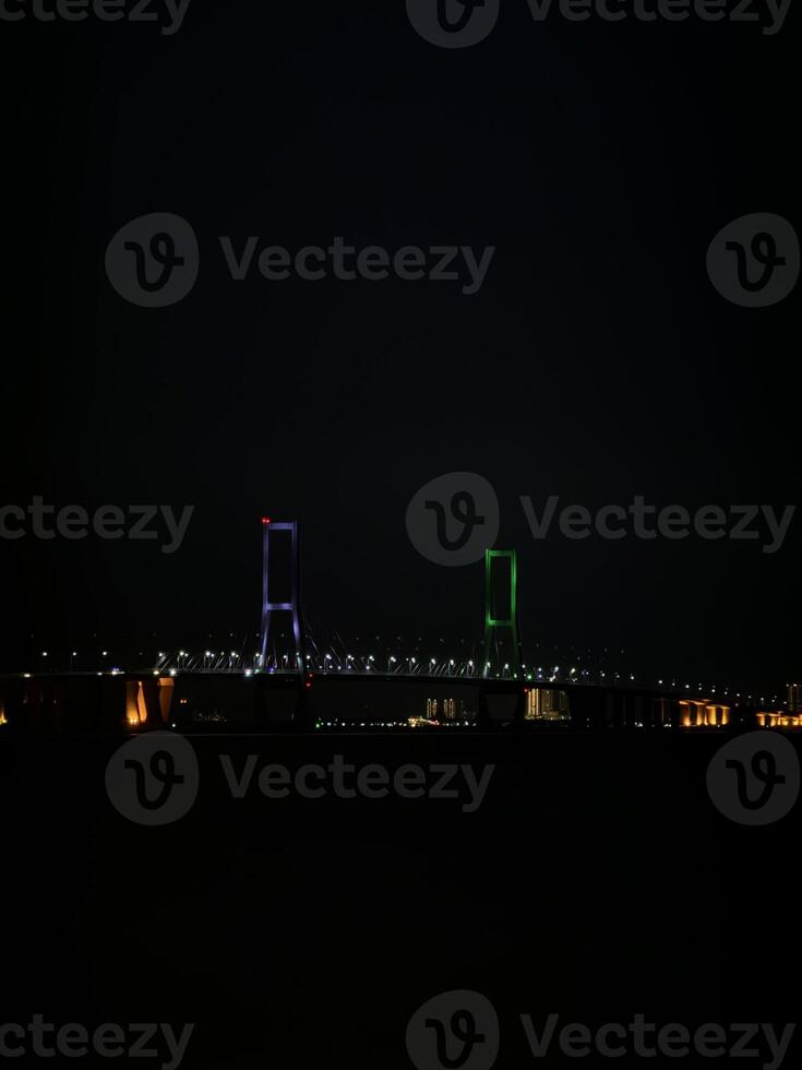 Suramadu Bridge Over Madura Strait with Calm Ocean and Blue Sky. Longest Cable-Stayed Bridge in Indonesia, Coastal View, Urban Skyline, Maritime Landmark, Travel Destination, Tourism, Architecture. photo