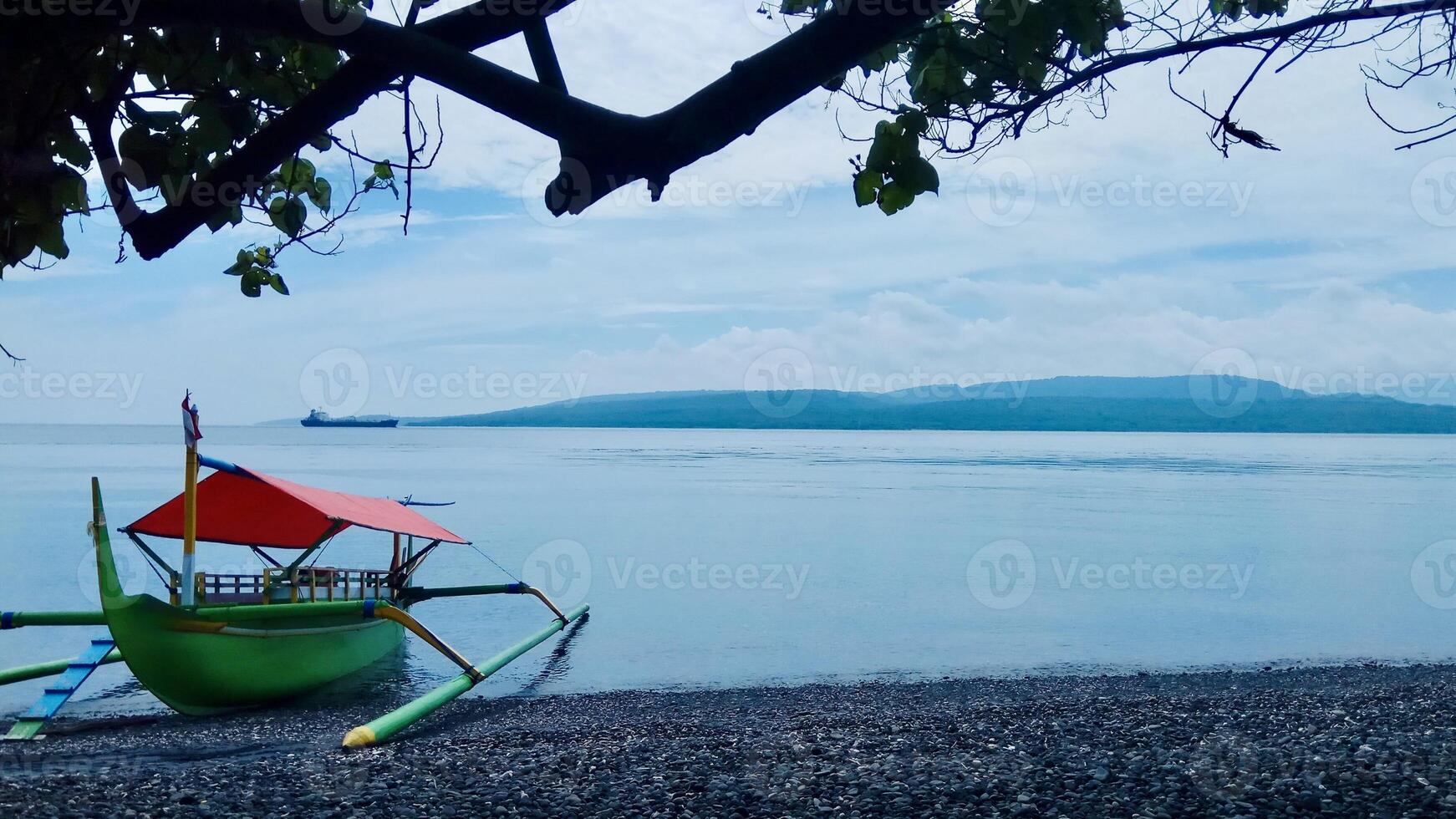 Traditional Outrigger Boat on Pebble Beach. Watu Dodol Banyuwangi photo