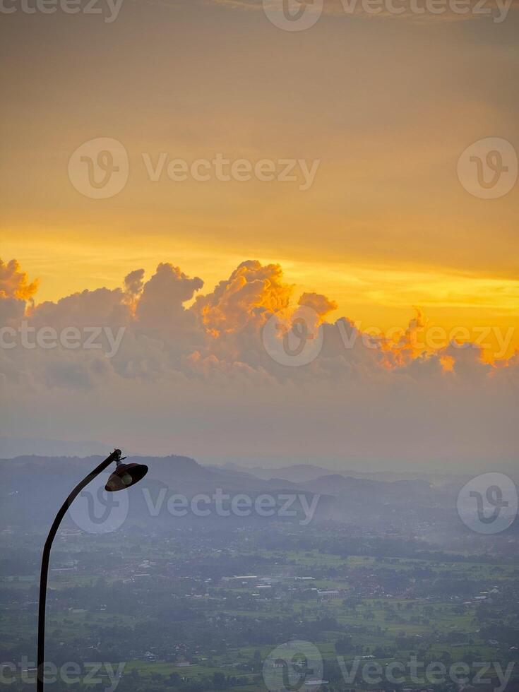 Golden Sunset Over a Misty Valley with a Rustic Street Lamp photo