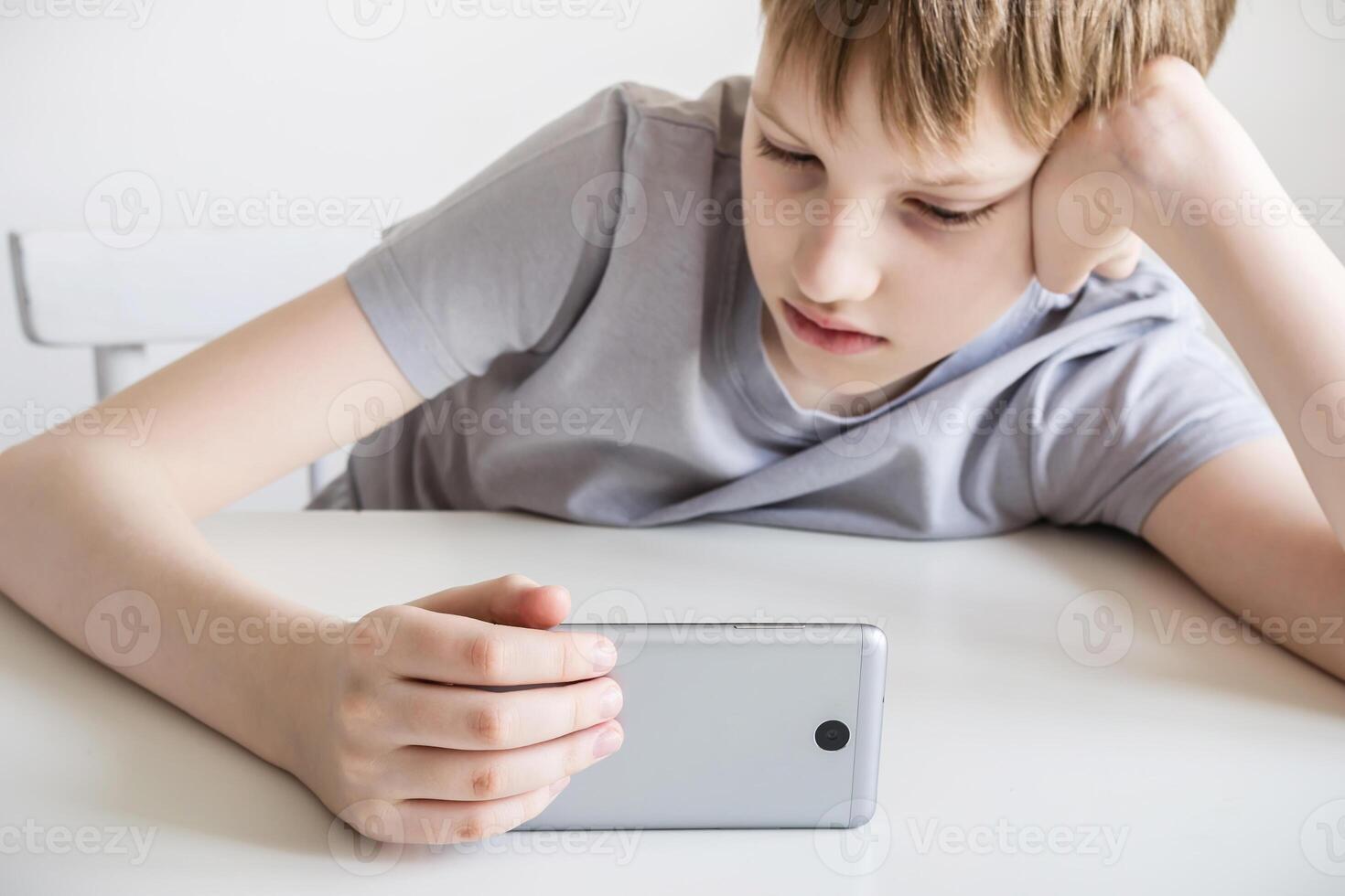 Teen boy watching in smartphone. Selective focus on smartphone photo
