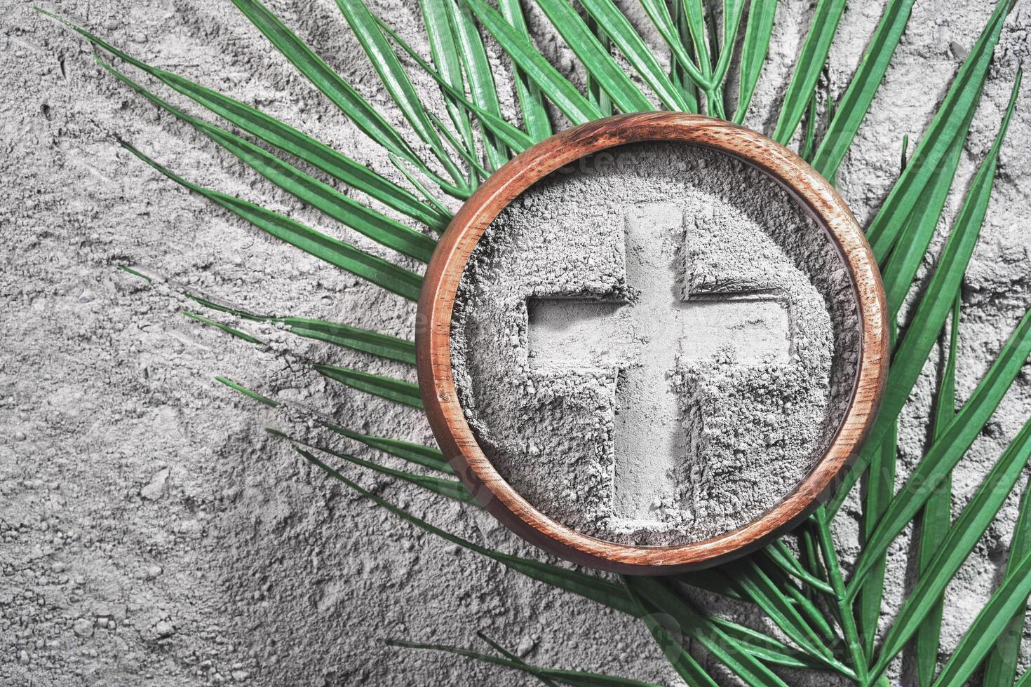 Bowl with ashes with cross print and palm branches on ash background. Ash Wednesday photo