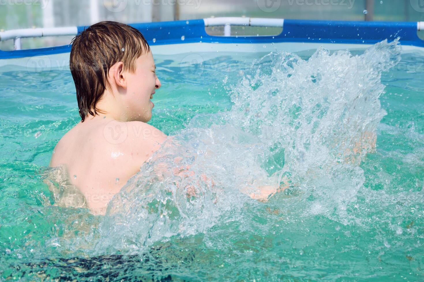 Happy boy splashing on summer pool photo
