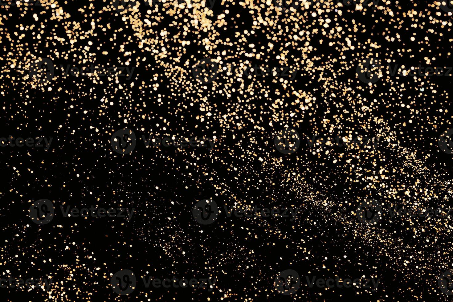 Abstract scattering of gold sparkles on black. Holiday backdrop photo