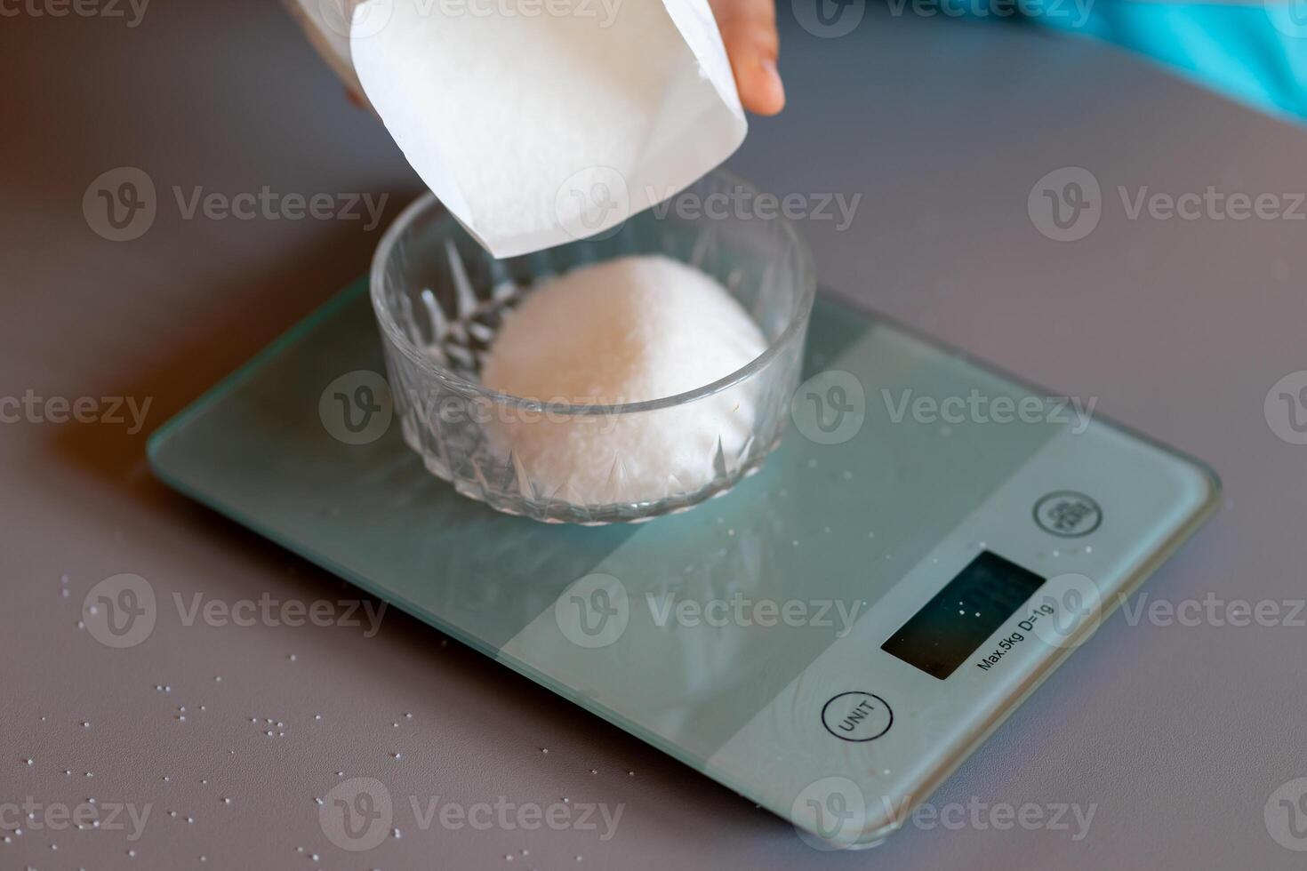 View of a weighing sugar from a pack on a kitchen scale on the kitchen table photo