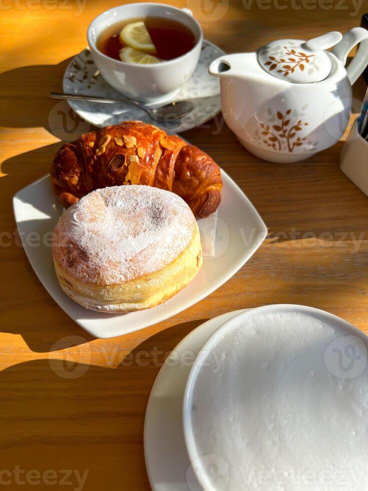View of the table set for breakfast with tea and sweet pastries in the sun photo