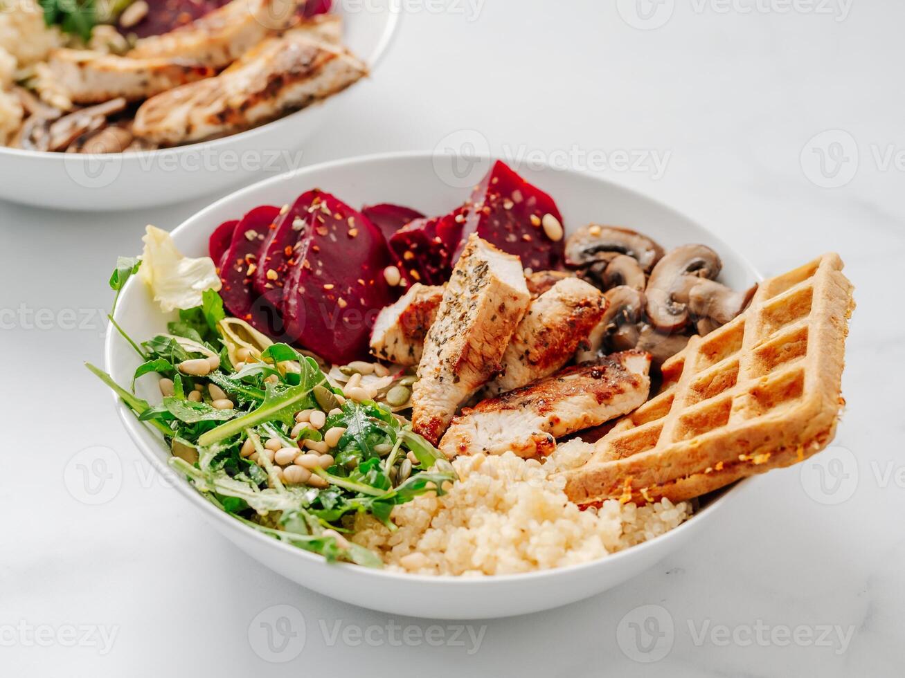 Bowl with grilled chicken, mushrooms, beetroot, quinoa, green rucola, decorated pine nuts and carrot waffle. Top view of gourmet bowl. Balanced gourmet dish on black wooden background. Healthy Food photo