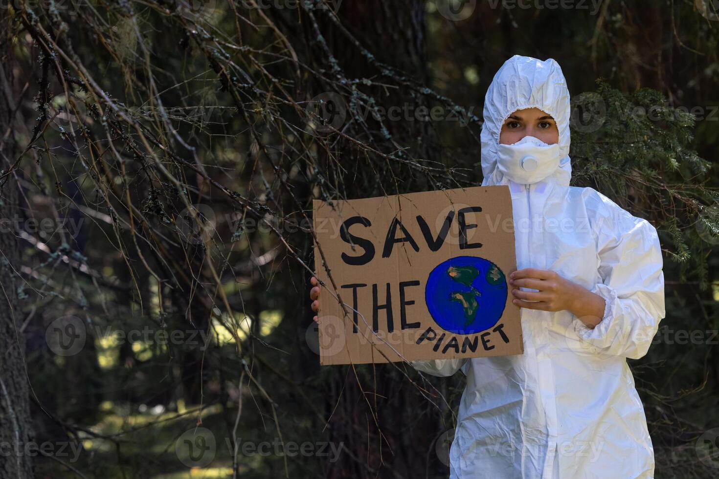 Doctor in a white anti-epidemic suit holding a cardboard banner in hands photo