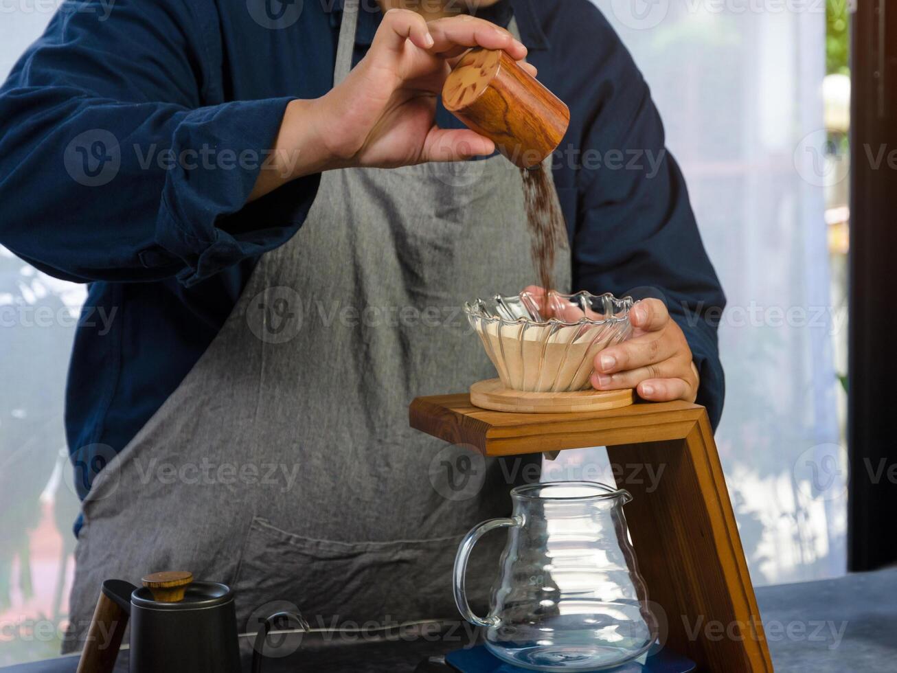 Coffee drip maker. Barista pouring ground coffee in paper filter photo