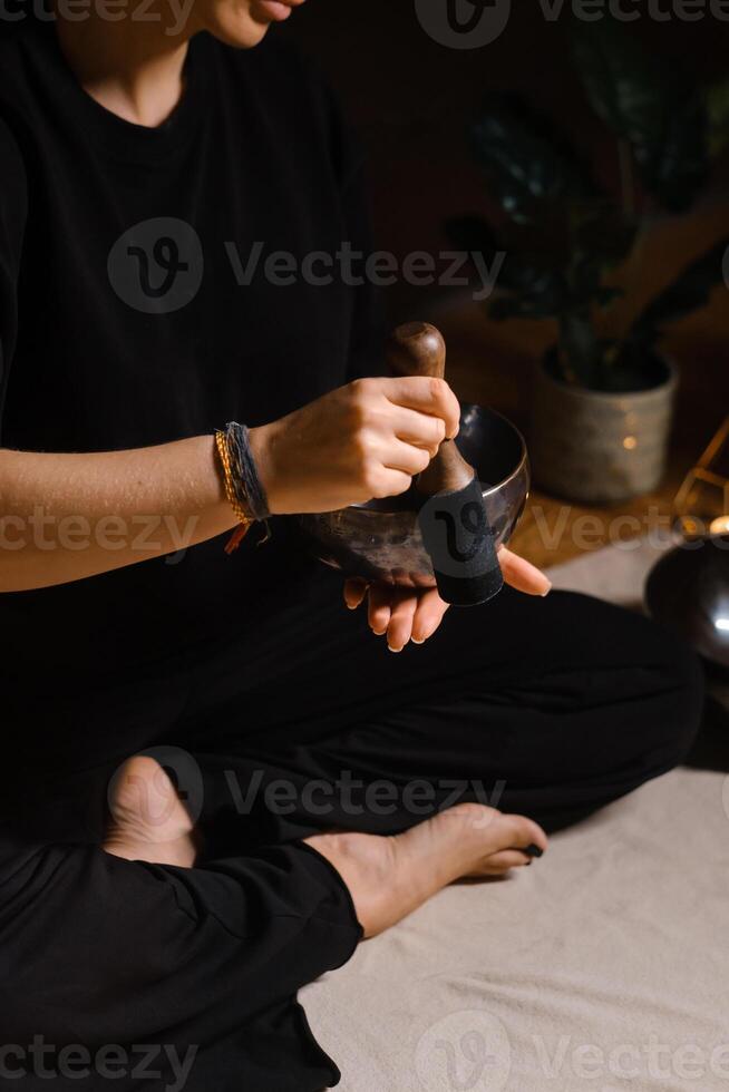 Practitioner uses singing bowls for meditation in a serene studio environment during a mindful evening session photo