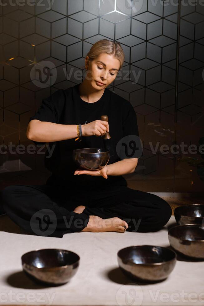 Practitioner uses singing bowls for meditation in a serene studio environment during a mindful evening session photo