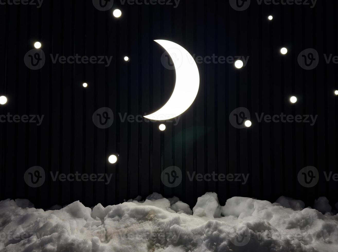 A luminous crescent moon and twinkling stars shine against a dark backdrop, casting a soft glow over the snow below. The minimalistic night sky installation creates a dreamy and serene winter photo