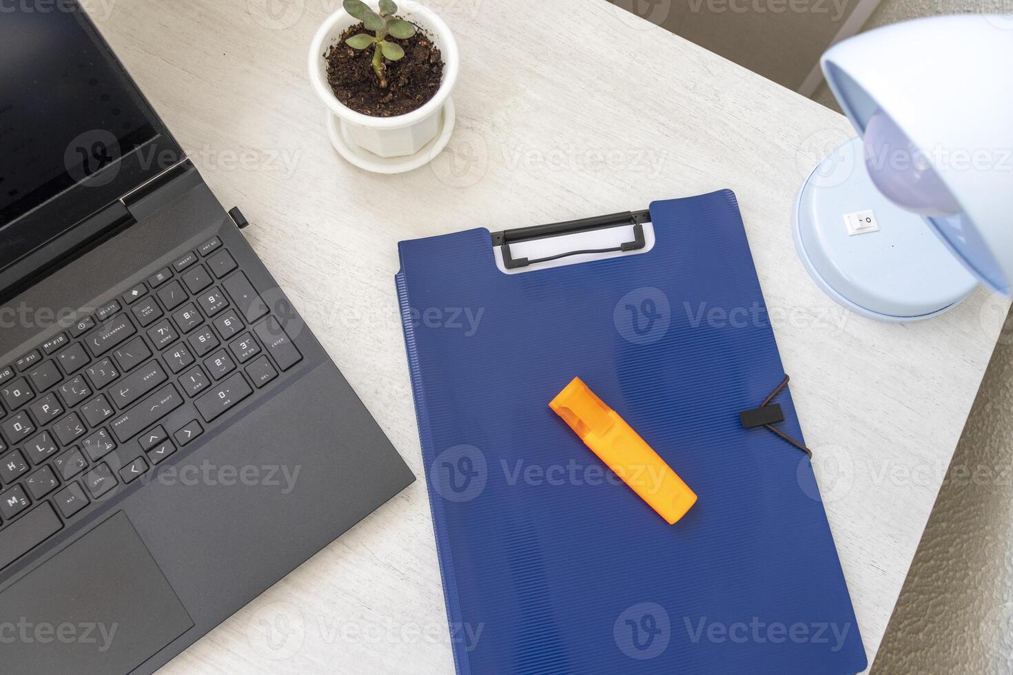 Shot of the blue folder on the office desk with paper clip holder on the top and other office items. A4 size paper mock up. Stationary photo