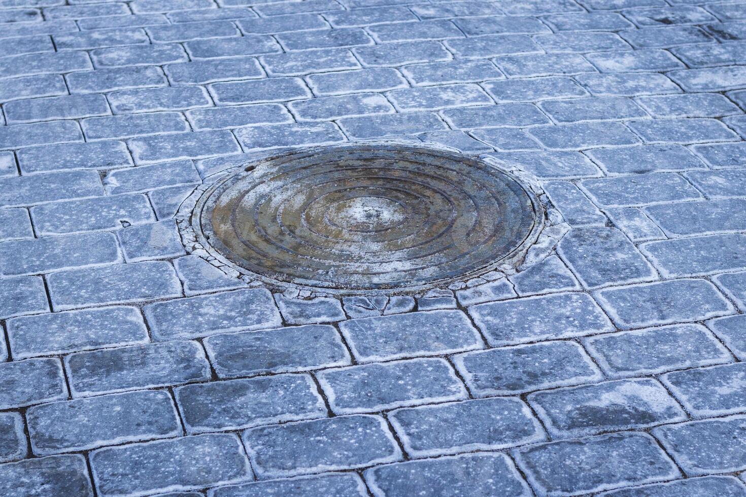 Manhole and interlock bricks with frost on them. Texture photo