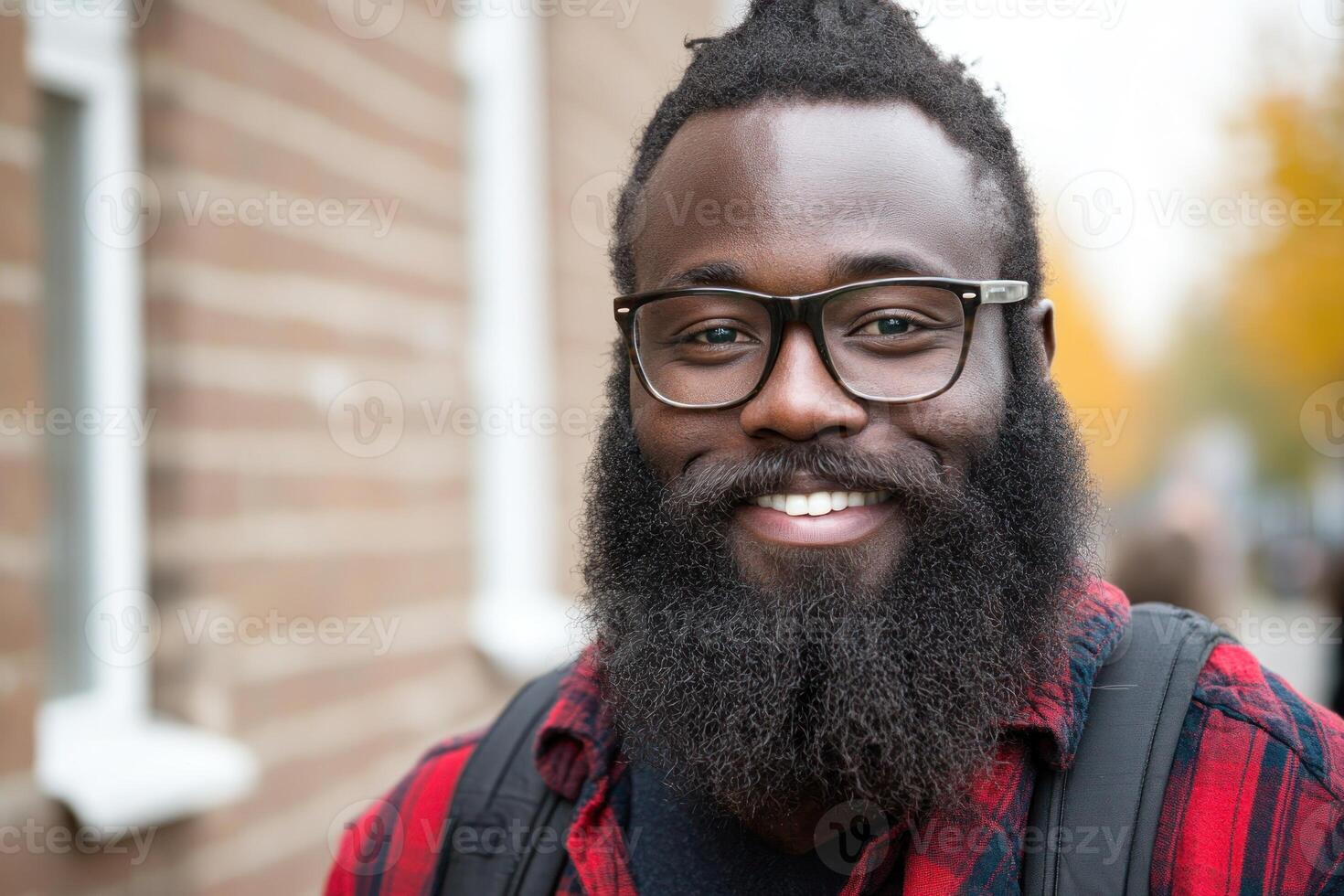 Man with beard smiles outdoors in urban setting during autumn afternoon photo