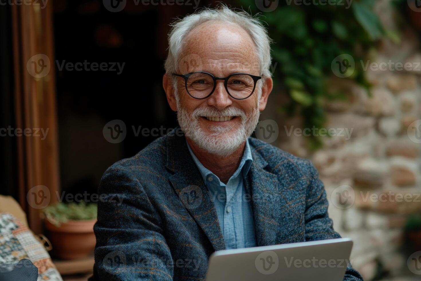 Senior man smiling while working on laptop in cozy indoor setting with natural light photo