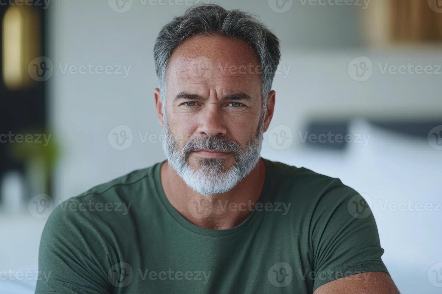 Mature man with a beard reflects quietly in a modern indoor space during daylight hours photo