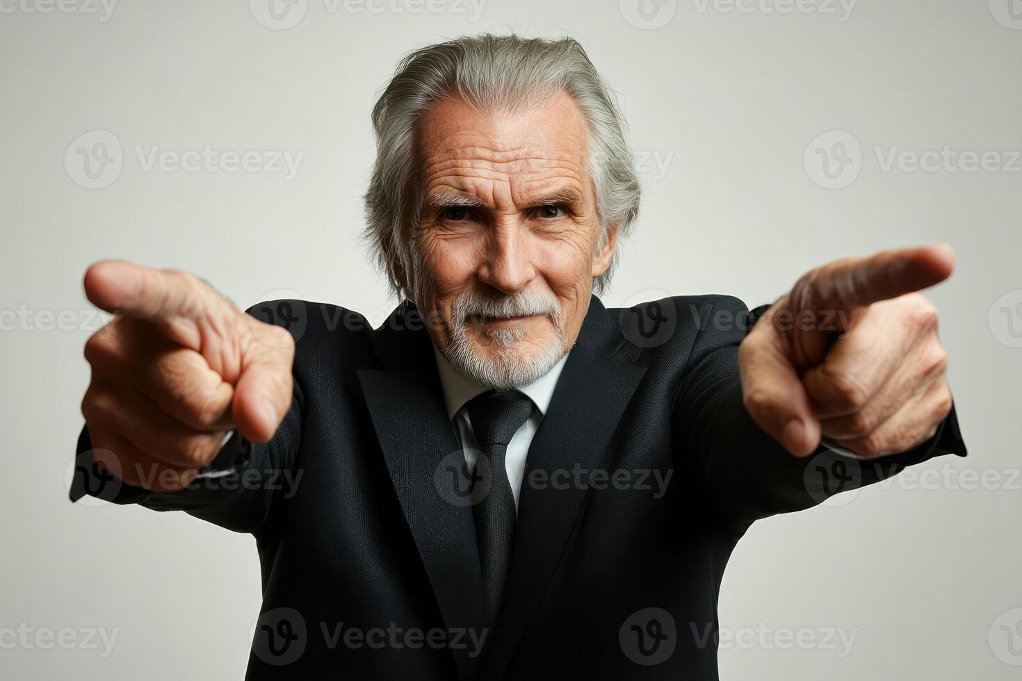 Elderly man in formal attire pointing at the camera with a confident expression indoors photo