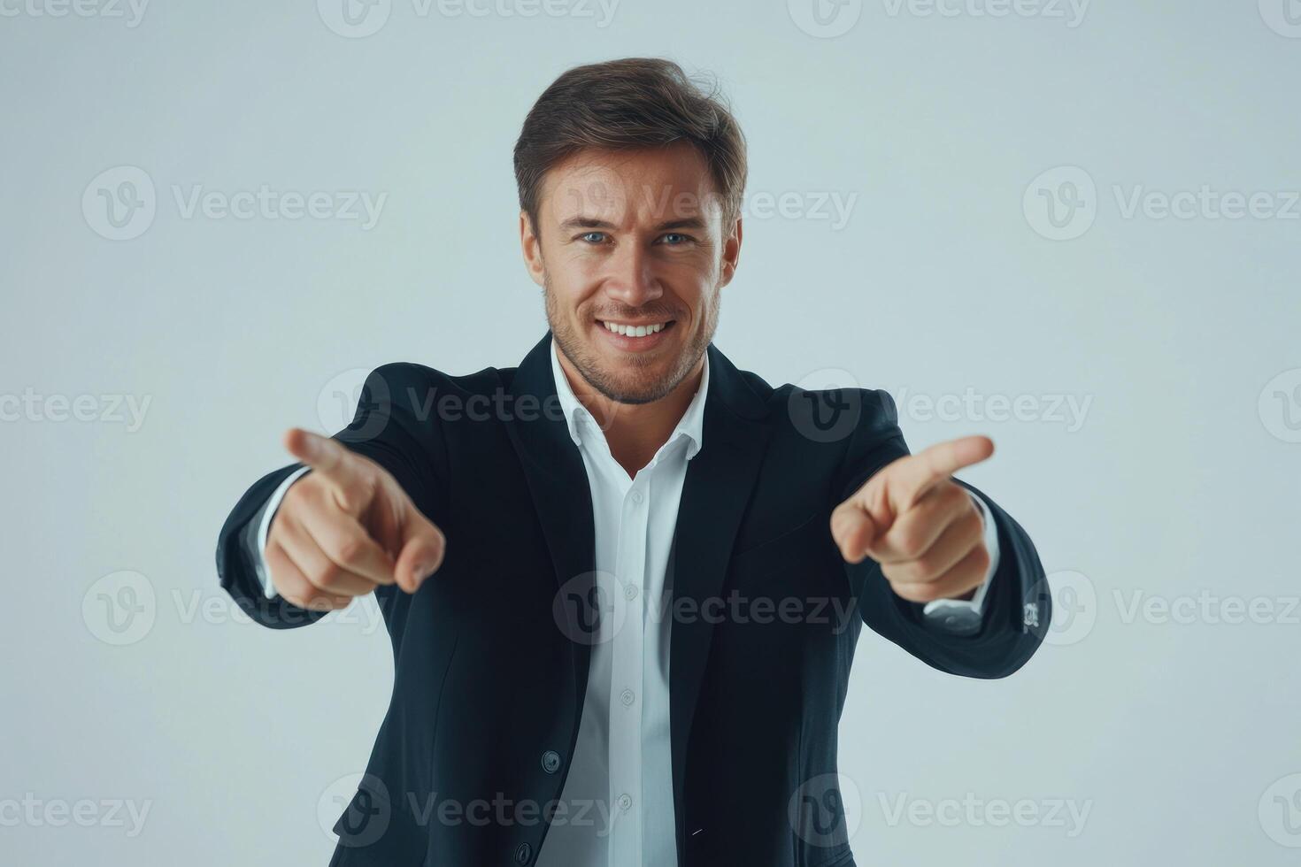 Confident man pointing and smiling in professional attire against a light background photo