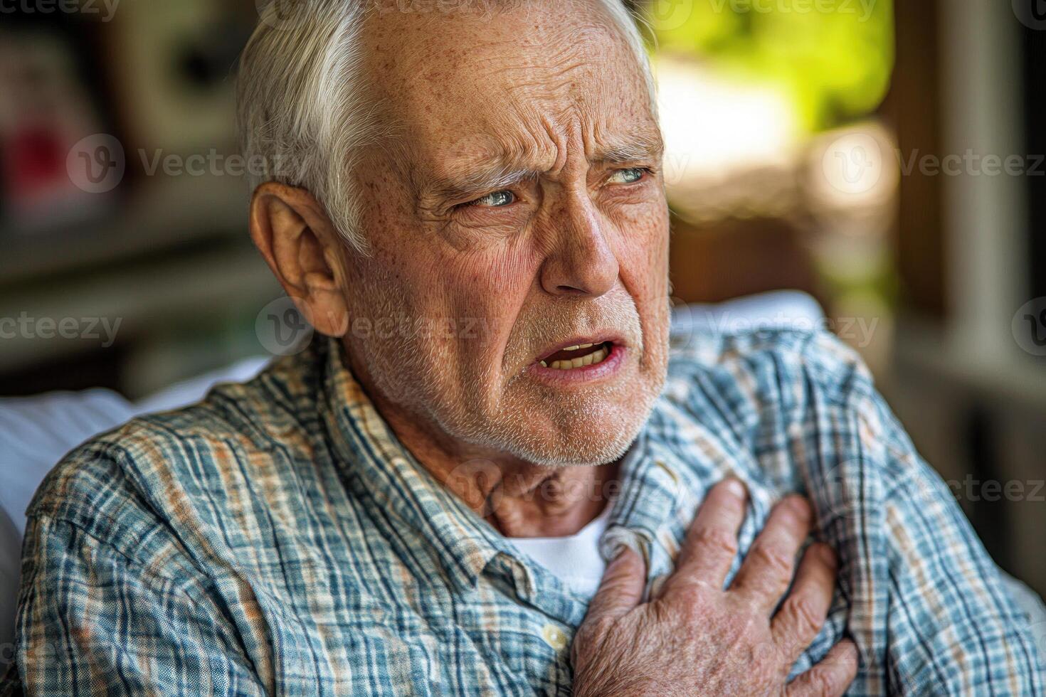 Senior man experiencing chest discomfort while seated indoors during daylight photo