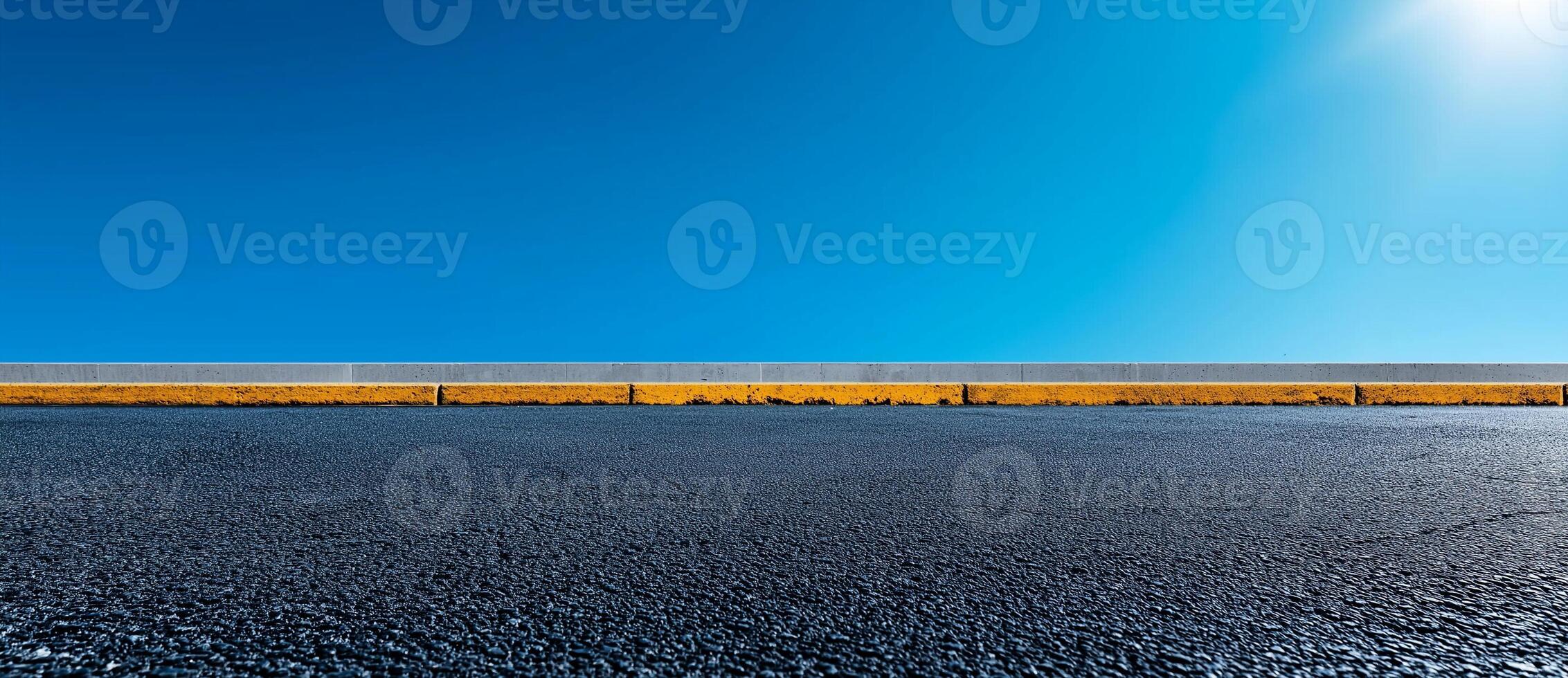 clear blue sky above smooth asphalt road with concrete curb. scene conveys sense of openness and tranquility, perfect for backgrounds or design projects photo