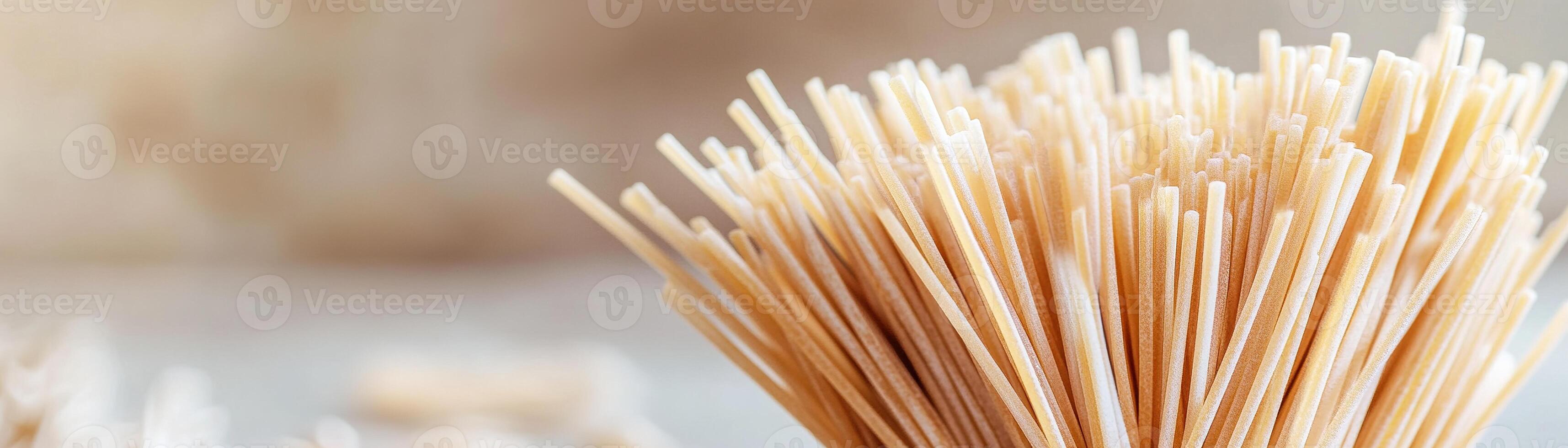 Golden spaghetti strands are captured in a close-up view, showcasing their gourmet texture against a softly blurred warm background, perfect for culinary branding photo