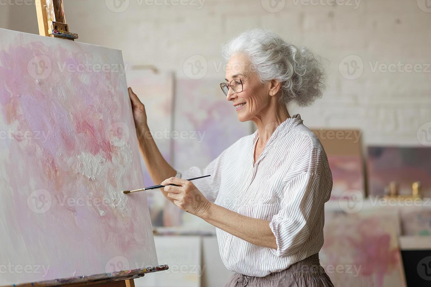 In a spacious studio filled with soft, golden-hour light, a graceful senior woman joyfully paints an abstract canvas, surrounded by a dreamy artistic atmosphere and ample creative space photo