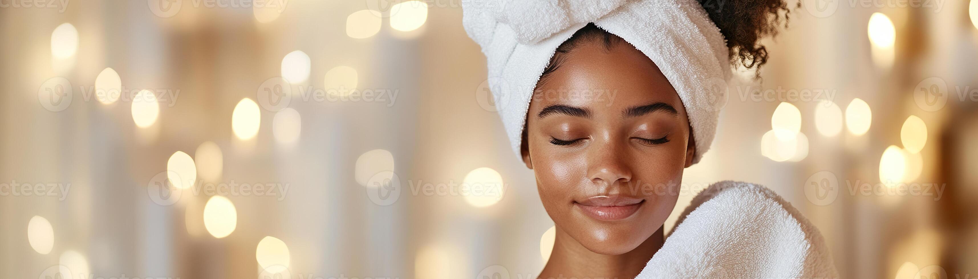A woman enjoys a moment of tranquility while wrapping her damp hair in a plush white towel after a deep conditioning treatment, surrounded by warm candlelight photo