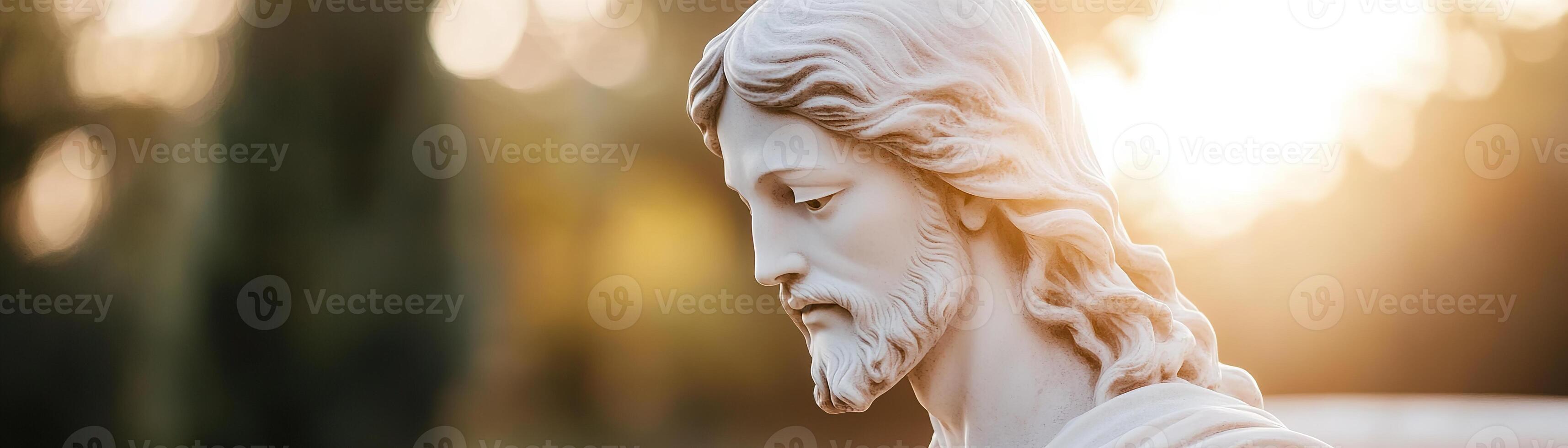 A detailed statue of Jesus with a serene expression is highlighted by warm sunlight filtering through trees, creating a peaceful, divine atmosphere photo