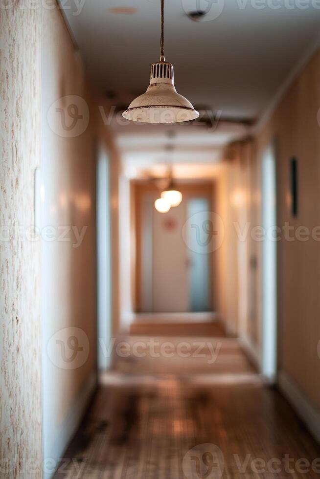 Long and narrow hostel hallway shows scuffed wooden floors and faded wallpaper. Flickering ceiling lights cast eerie shadows, leading to distant doors that hint at untold stories photo