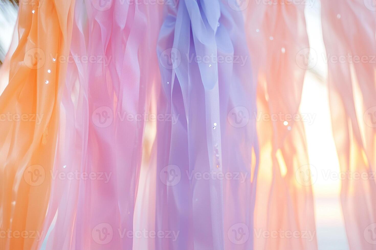 Cascading streamers transition from deep orange to coral pink and lavender, evoking a sunset. In the soft-focus background, palm silhouettes frame gentle ocean waves reflecting golden light photo