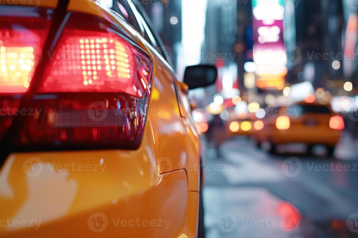 A yellow taxi waits at a busy intersection in Times Square on a rainy evening. The bright city lights reflect off the wet pavement, highlighting the vibrant atmosphere photo