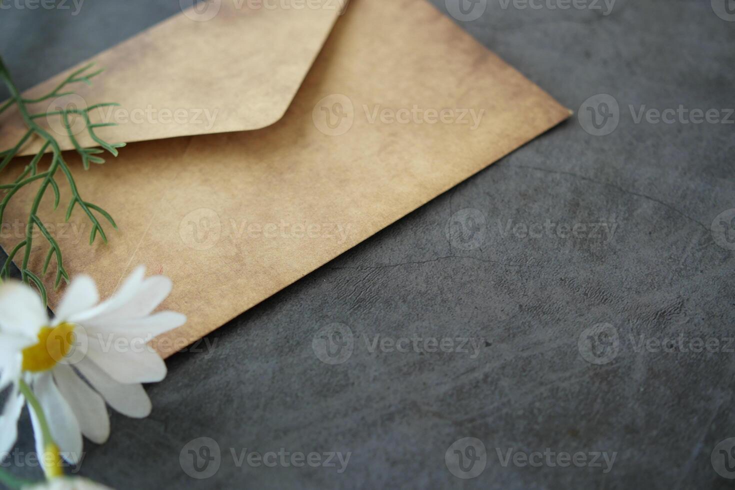 Nostalgic envelope on textured surface with white flower nearby photo