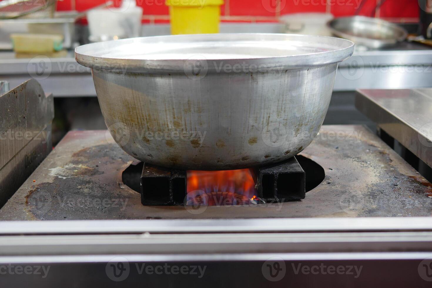 Cooking in a busy kitchen with a pot over a flame photo