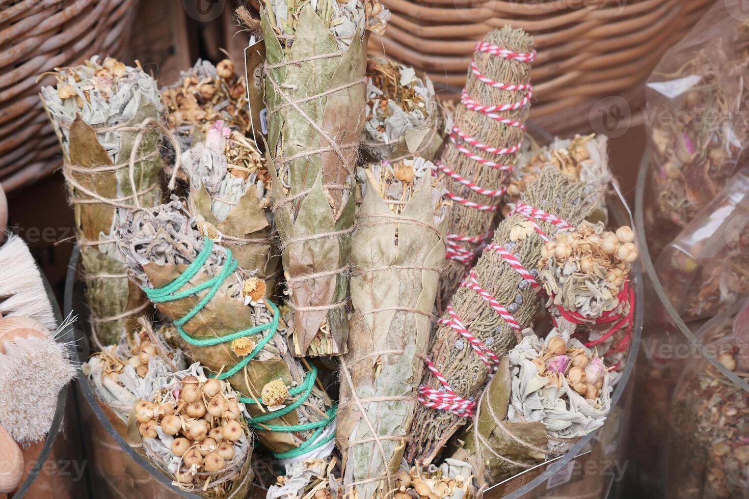 Various bundles of herbs and sage for smudging displayed in a market photo