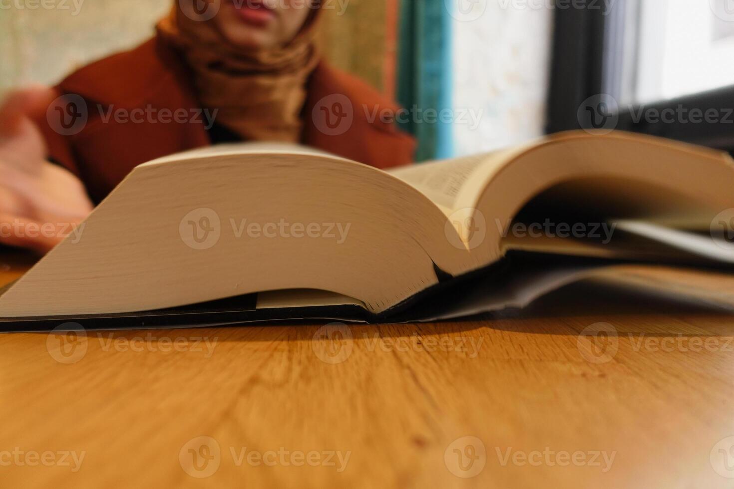 Person engaging in discussion over an open book at a cafe photo