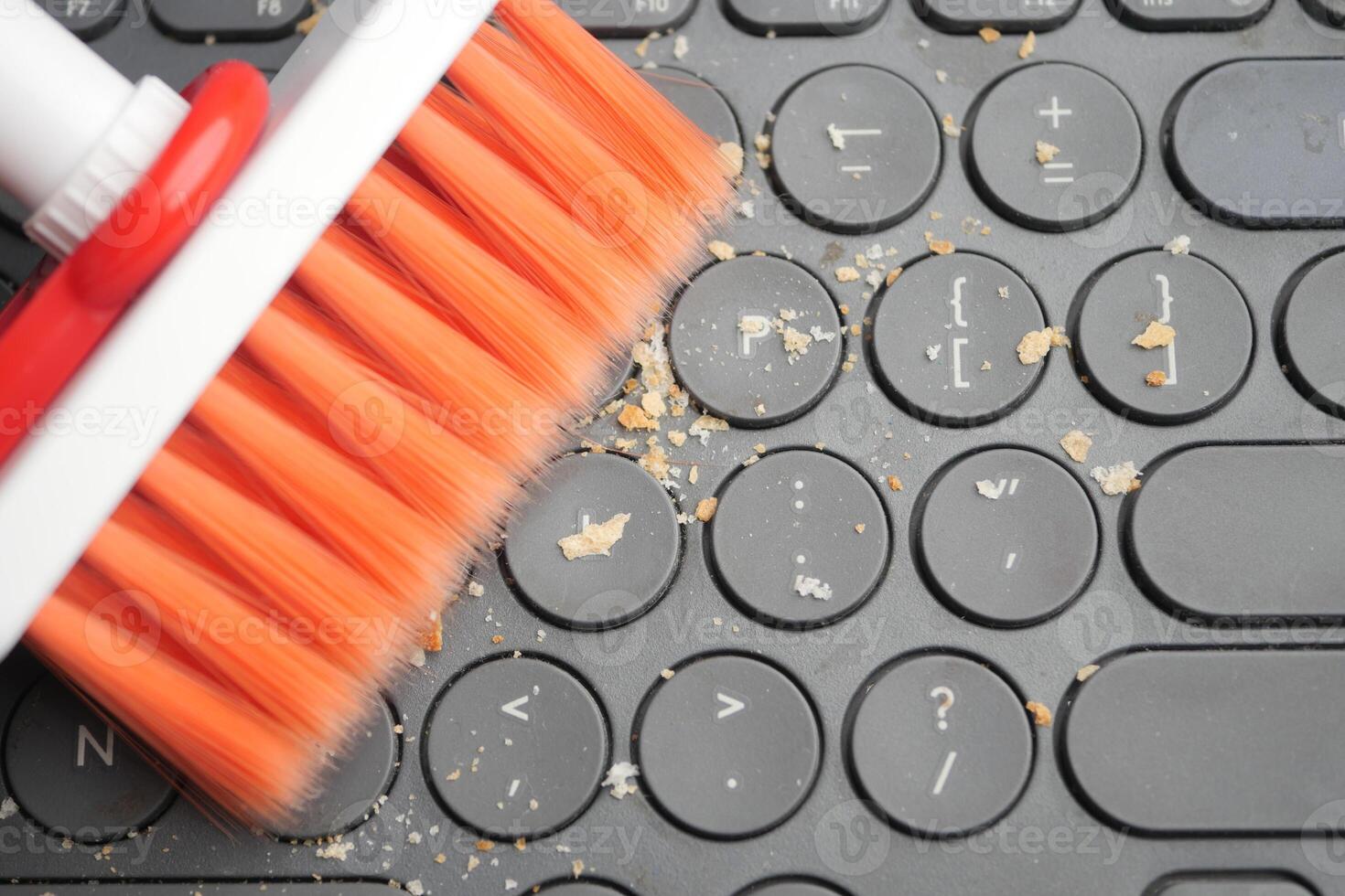 Cleaning a keyboard with a brush to remove debris and dirt photo