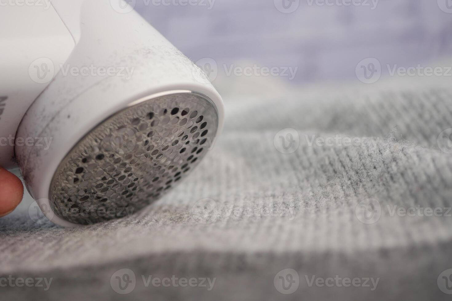 Fabric shaver removing lint from gray textile surface photo