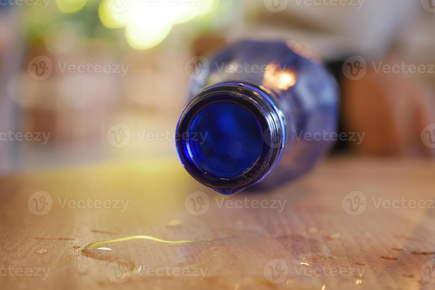 Water bottle spills on wooden table leaving a wet mark photo