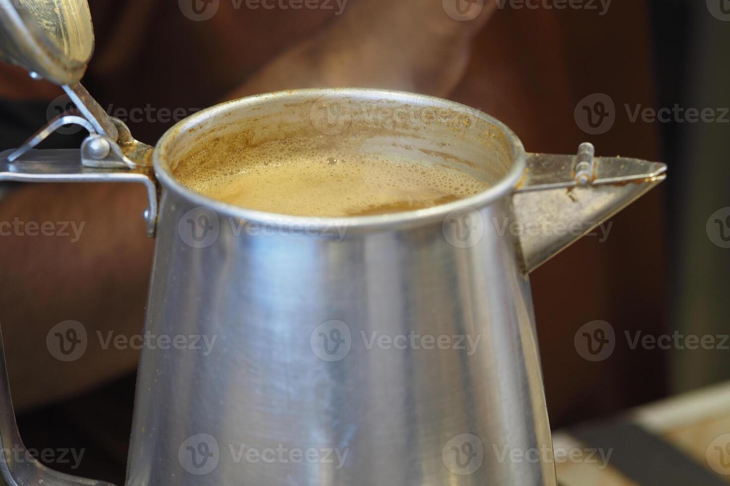 Brewing rich coffee in a traditional kettle at a cozy cafe photo