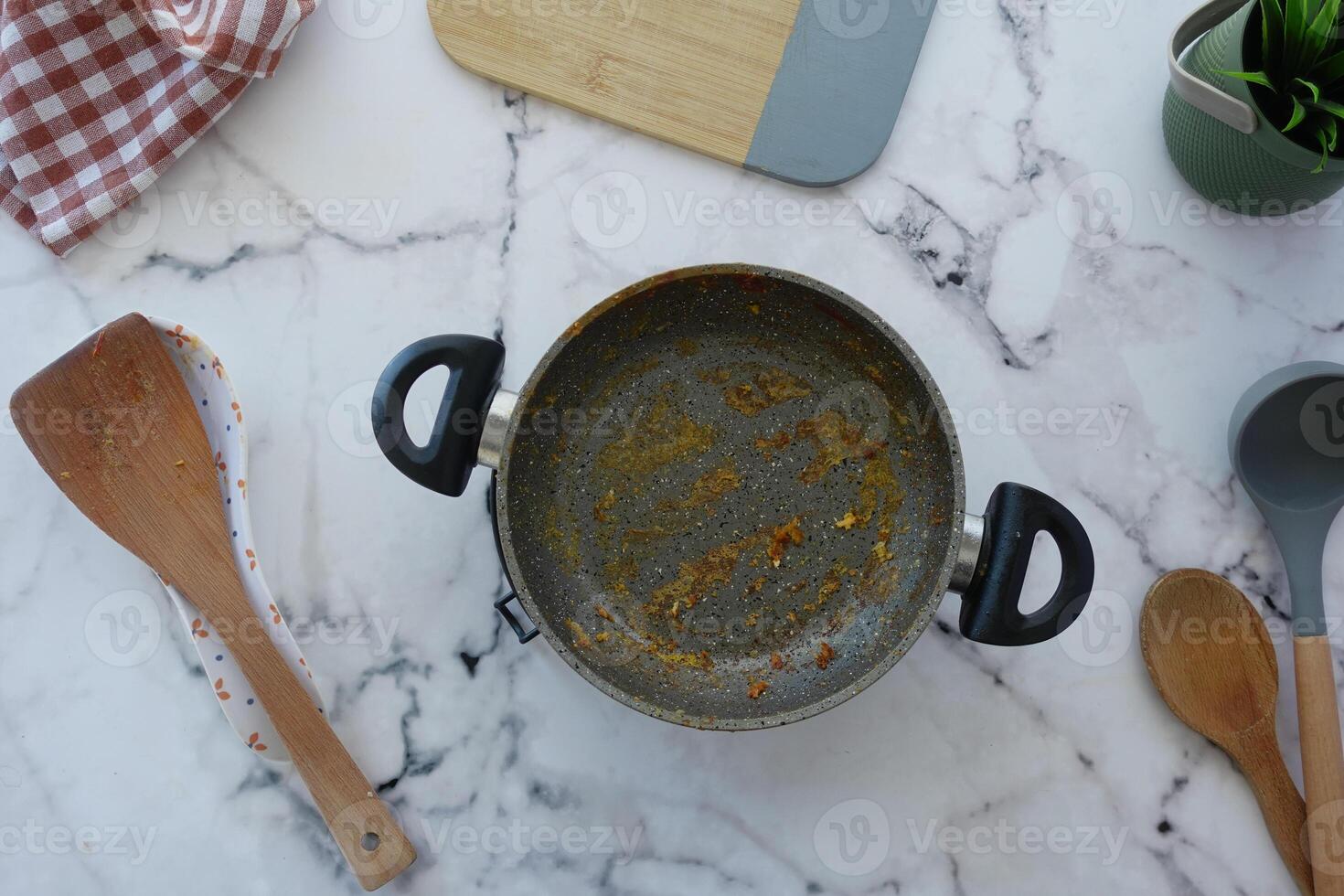 Cooking utensils and empty pot on a marble kitchen surface photo