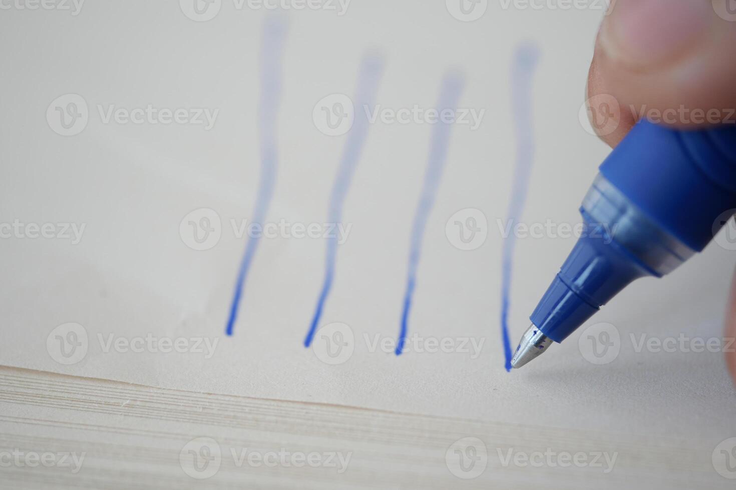 Writing with a blue pen on a blank page in a workspace photo
