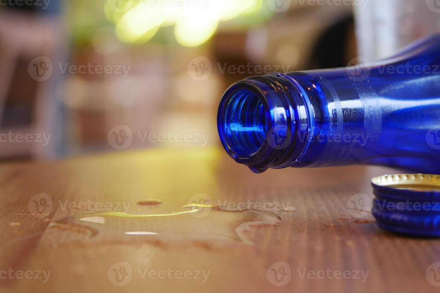 Blue glass bottle spills water on wooden table in bright cafe photo