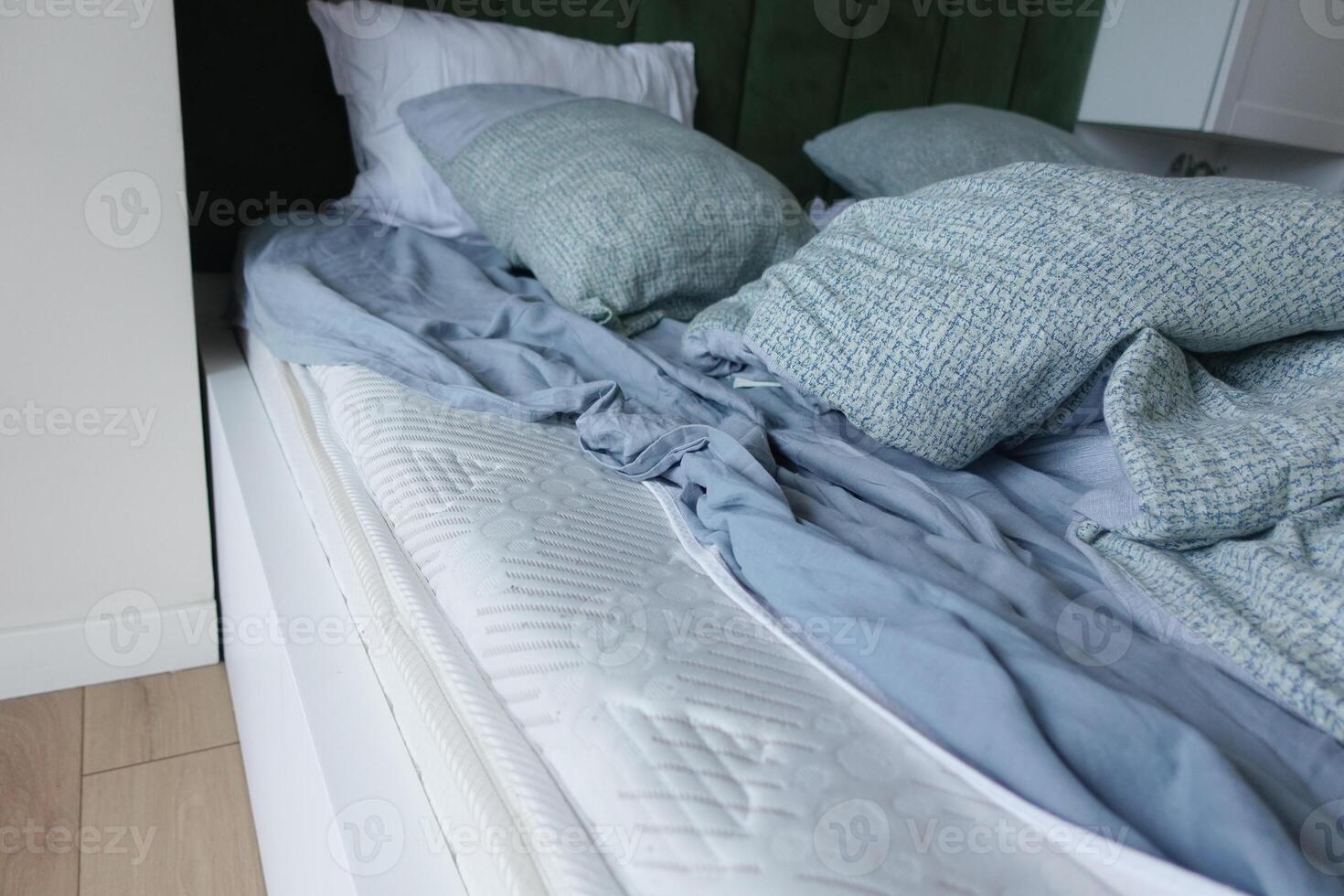 Cozy bedroom with unmade bed and soft pillows in fresh colors photo